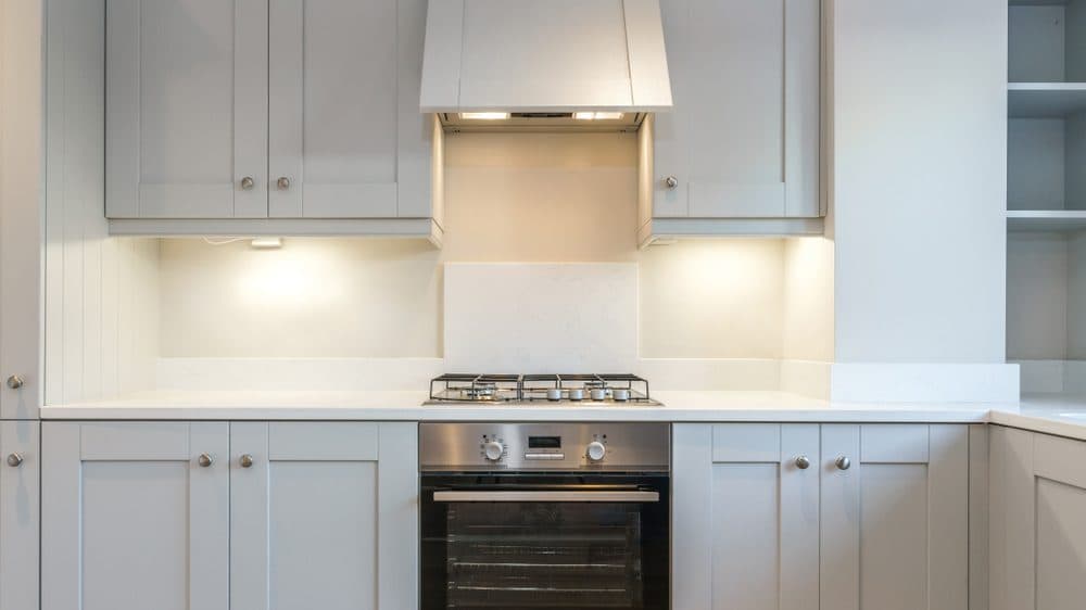 A white kitchen with under cabinet lighting above the stove top