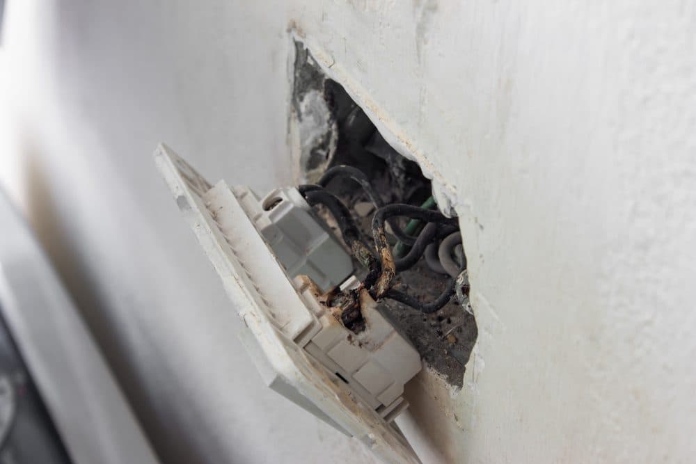 An outlet pulled out of the wall with wiring that looks faulty