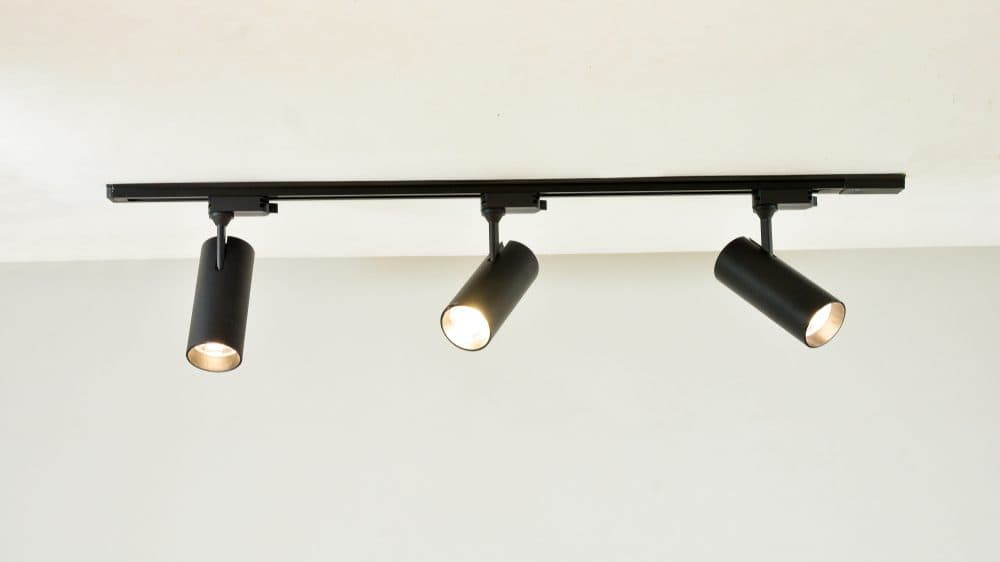 Three track lights on a black bar attached to the ceiling