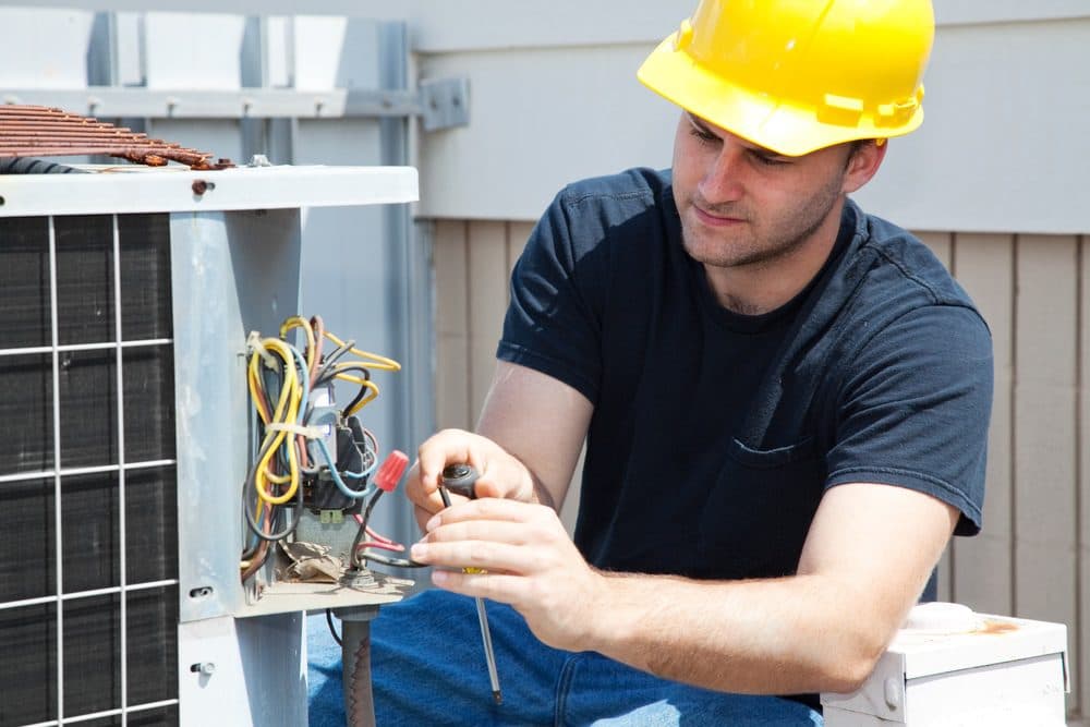 Technician repairing an air conditioner unit outside