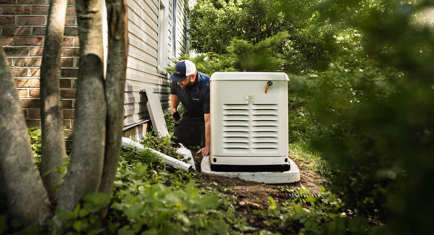 A professional Casteel technician inspects a large, beige whole-home standby generator installed on a concrete pad outside a residential house.