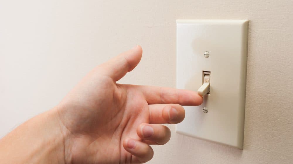 A hand flipping a light switch
