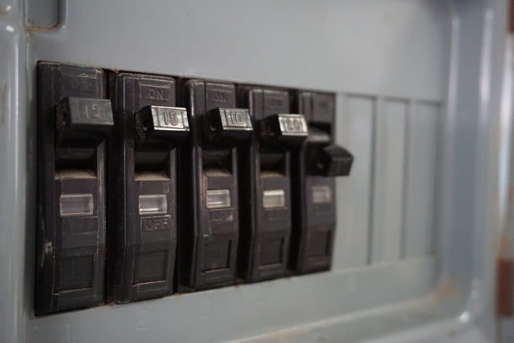 Five breakers in a circuit panel with the last one showing signs of damage