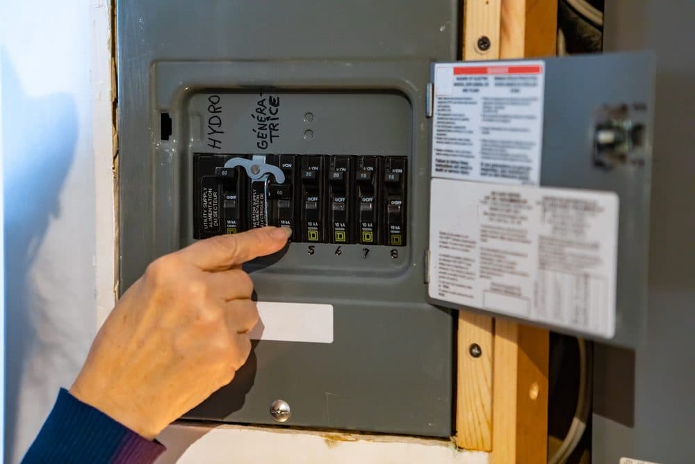 Casteel technician opening a circuit breaker panel and pointing at one of the breakers