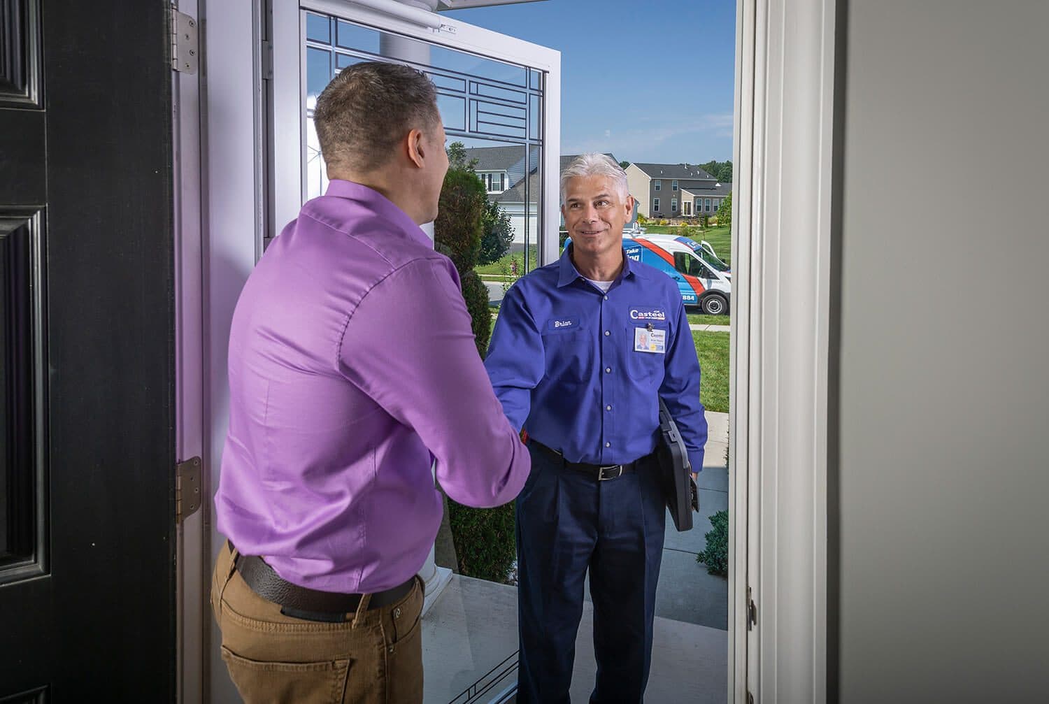 A smiling Casteel technician shakes the hand of a homeowner