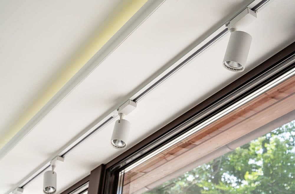 Several track lights above a window pointing inwards to the room