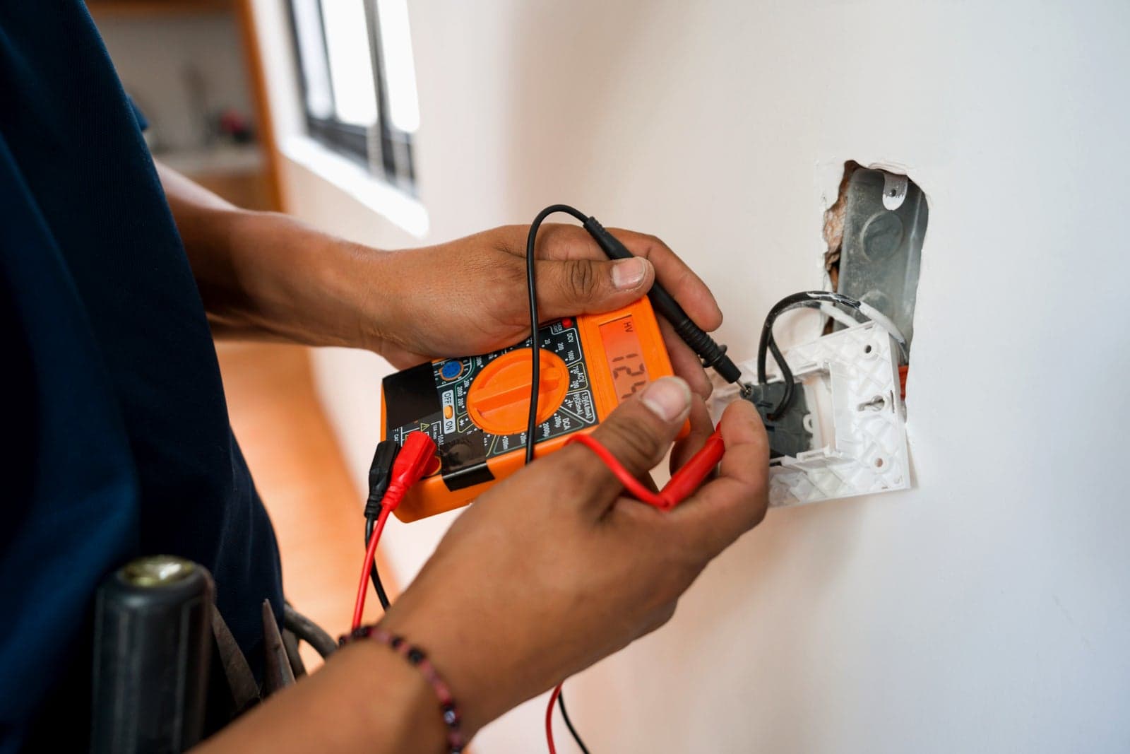 An electrician testing a buzzing light switch with a multimeter.
