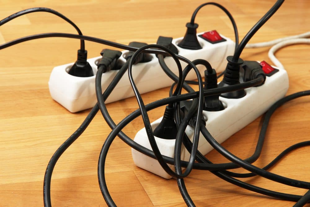 Two surge protectors that are full and overloaded with plugs