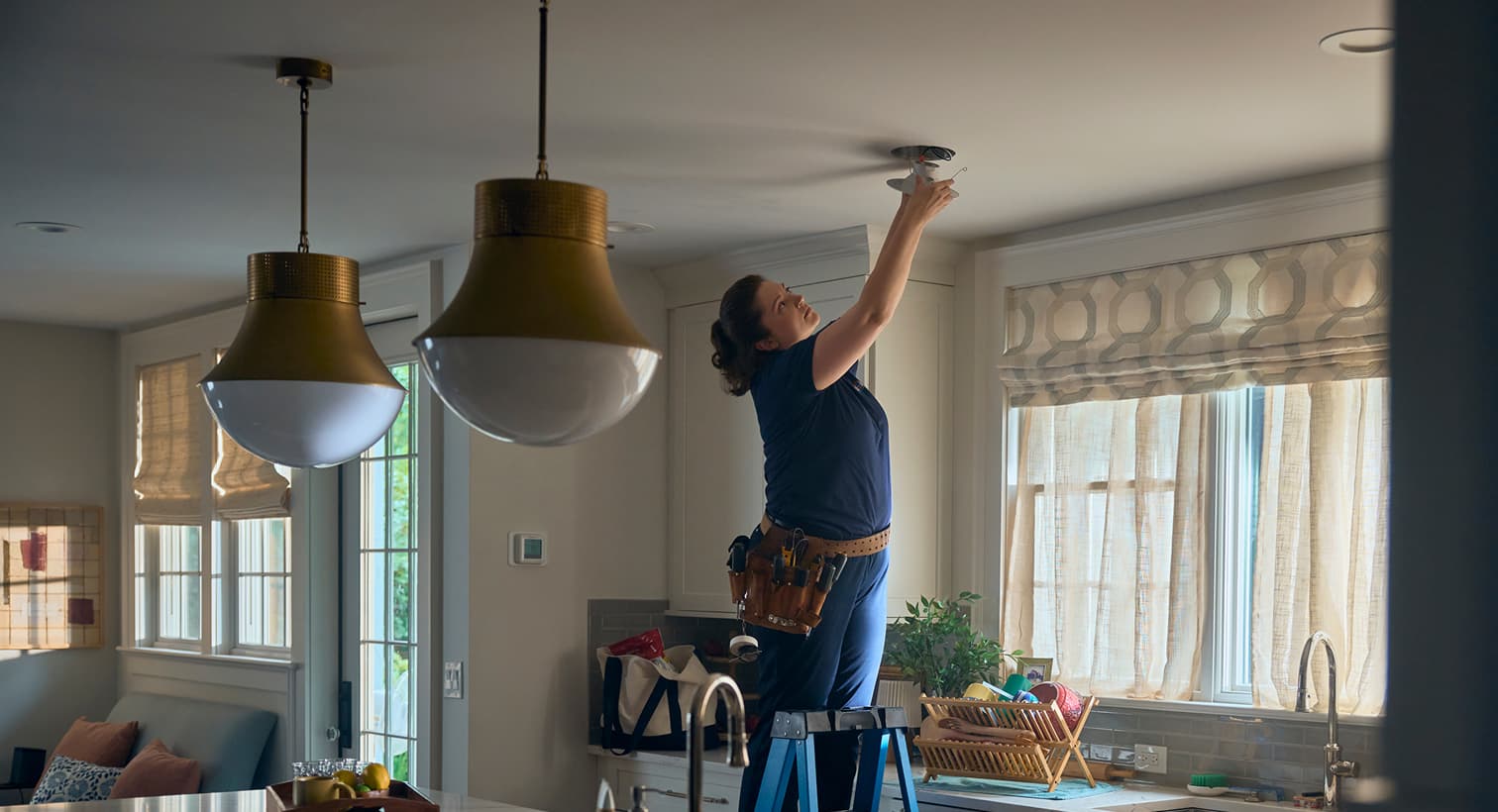 Casteel electrician installing a ceiling-mounted light fixture in a residential kitchen