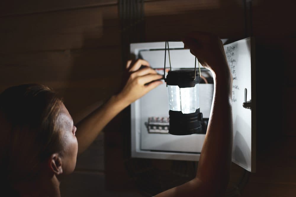 Casteel technician using a flash light to inspect an electrical panel while the power is out