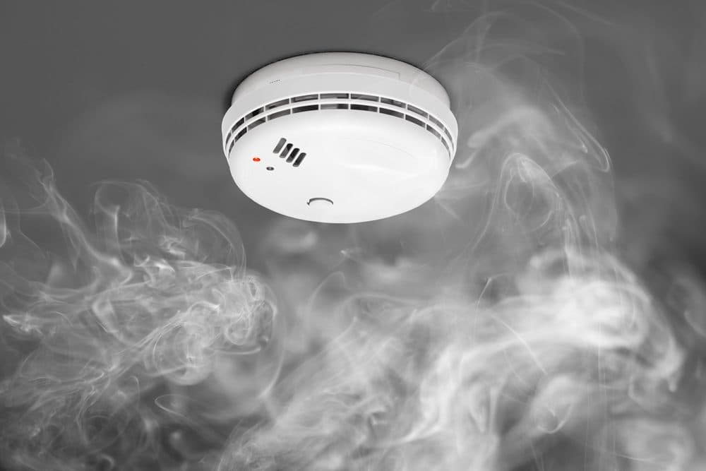A smoke detector with gray smoke around it